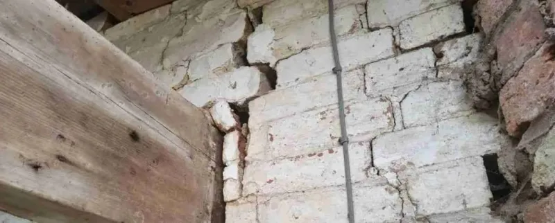 Close-up of structural brick wall damage requiring professional investigation